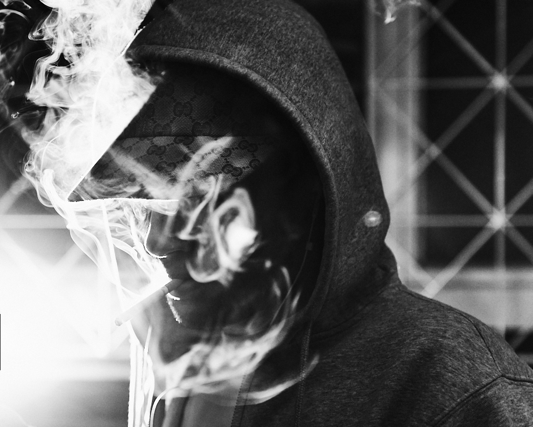 black and white hooded man smoking cigarette dramatic light portrait
