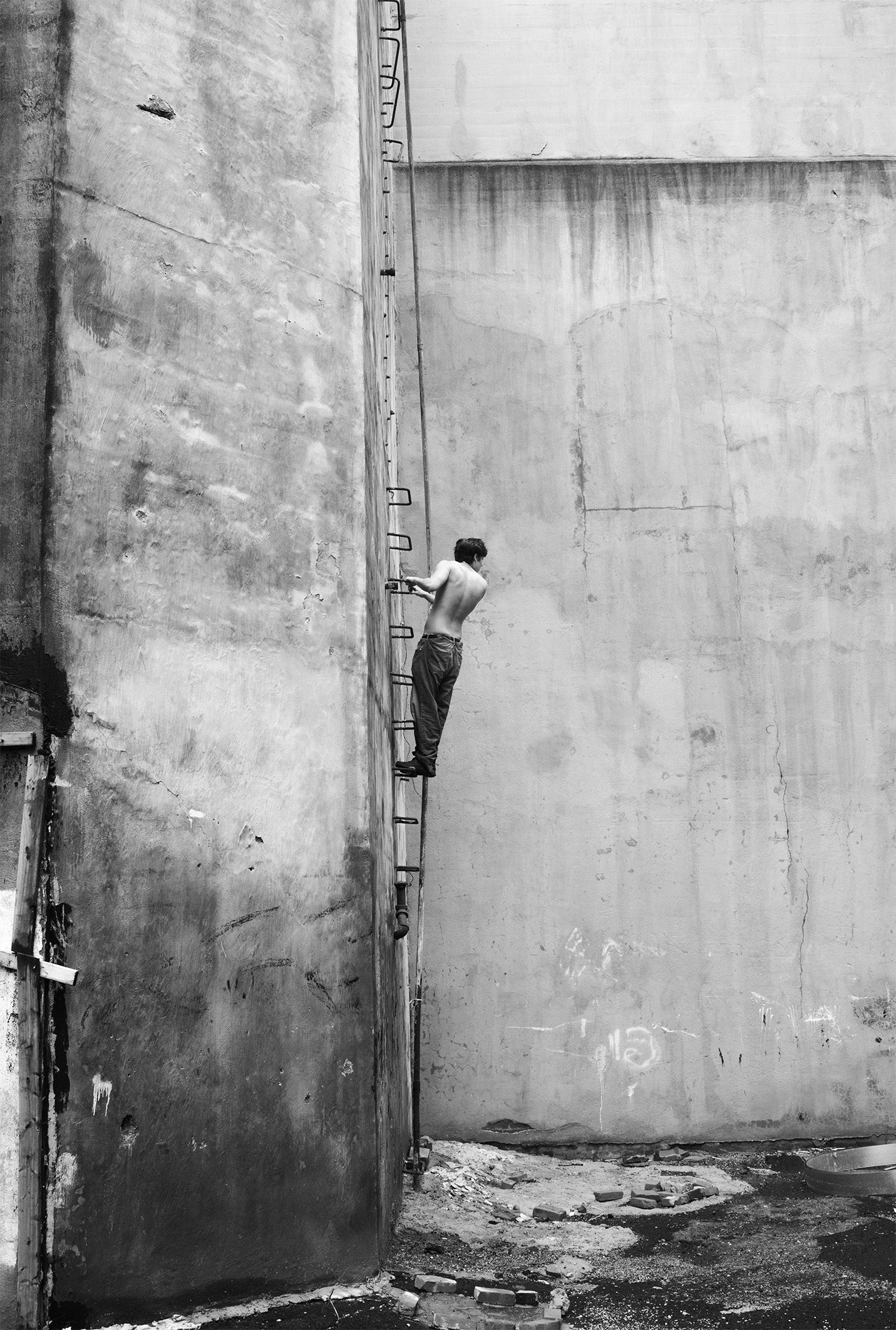 man climbing ladder concrete wall black and white conceptual
